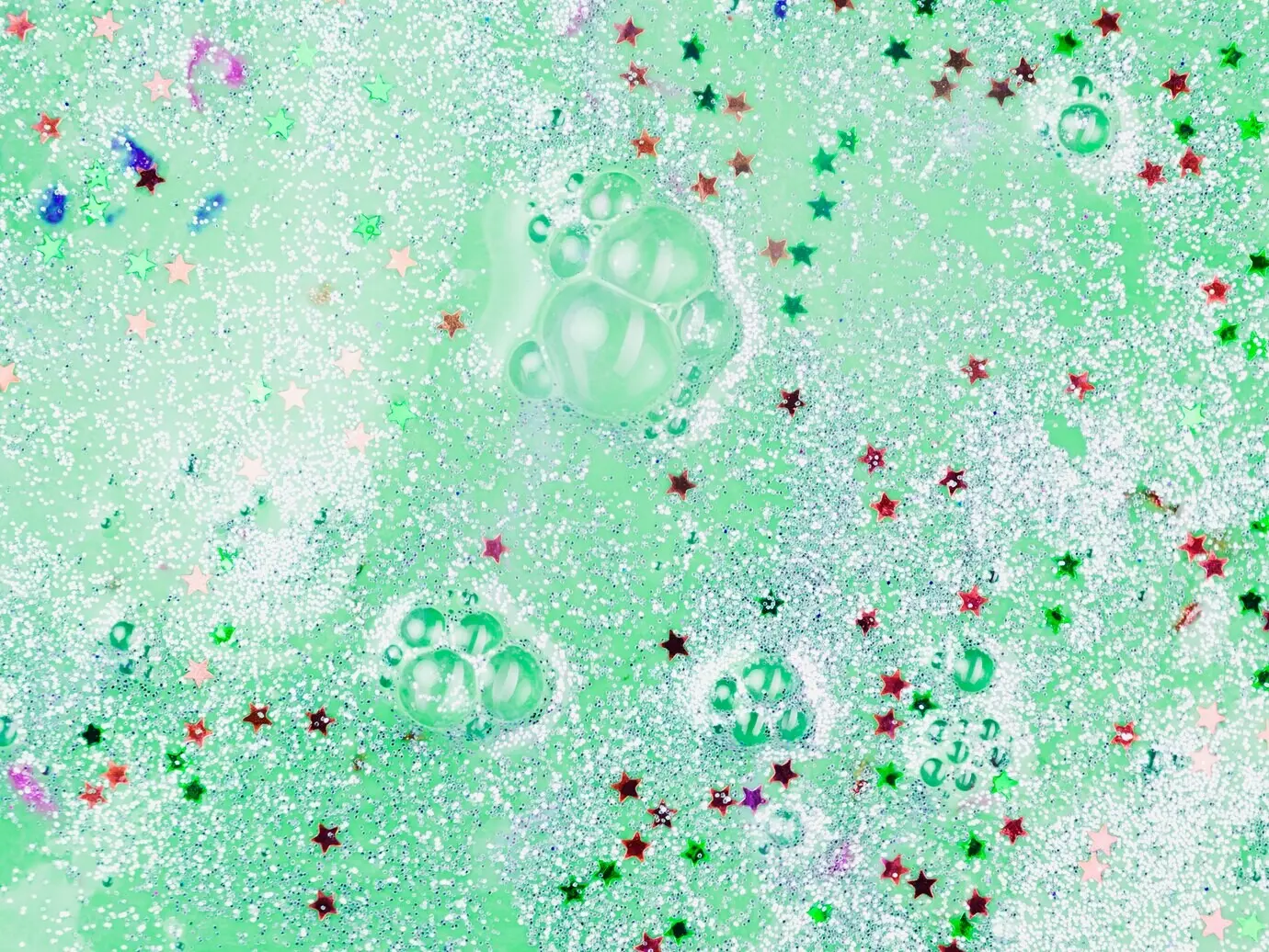 Agua pintada de color verde claro con adornos brillantes en forma de estrella y lentejuelas.